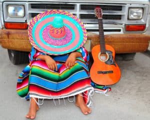 Lazy nap mexican guy sleeping on grunge car with guitar and poncho